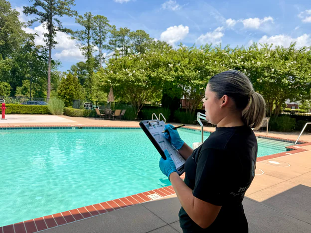 E3R Cleaning team lead checking a tablet checklist beside an apartment community pool